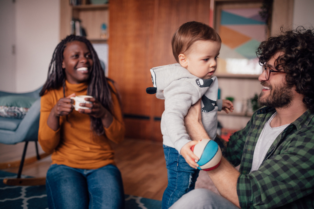 Man holding child with woman sitting next to them smiling.